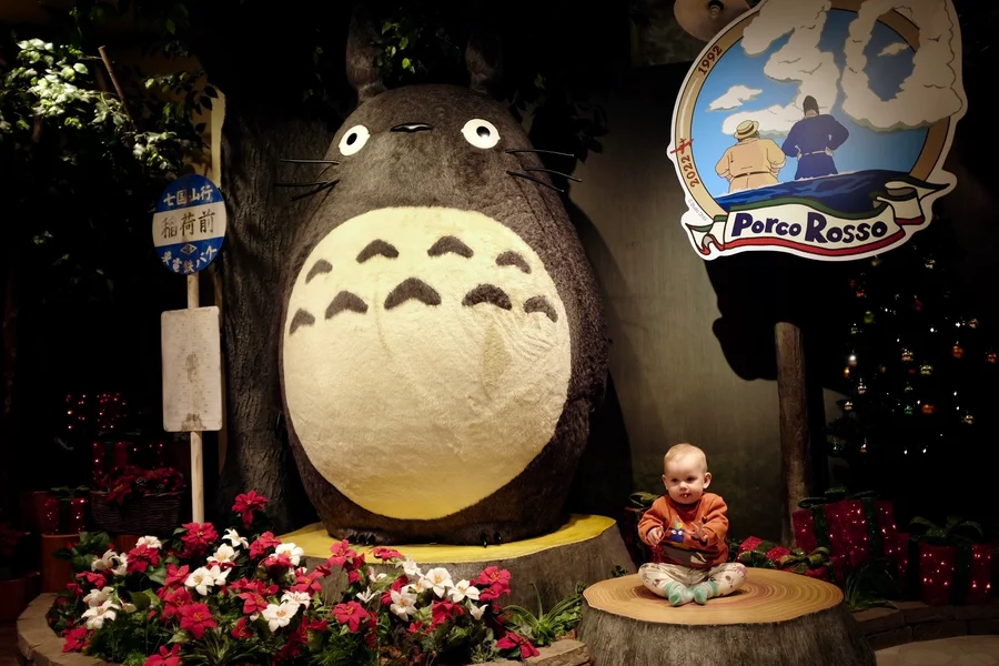 Baby sitting on a tree stump in front of a large Totoro statue at Donguri Kyowakoku, Tokyo Skytree Town Soramachi
