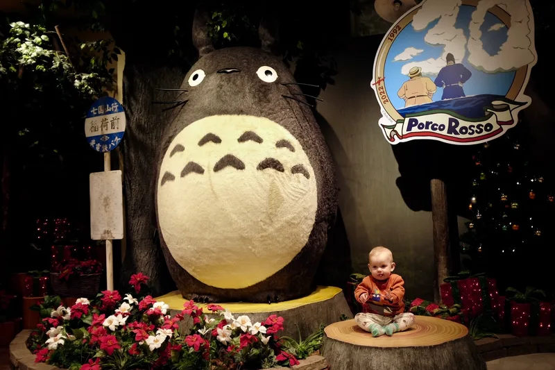 Baby sitting on a tree stump in front of a large Totoro statue at Donguri Kyowakoku, Tokyo Skytree Town Soramachi